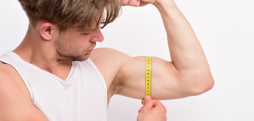 man measuring his bicep with a tape measure