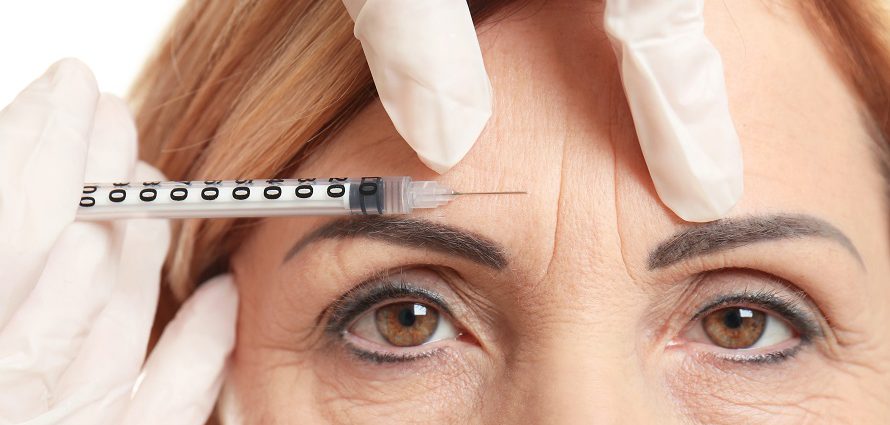 middle aged woman receiving botox injection to forehead