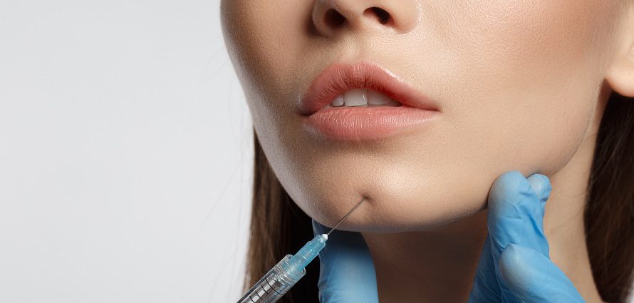 female patient getting a cosmetic injection to the chin