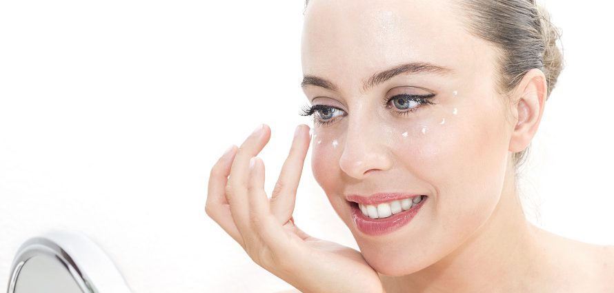 smiling female applying eye cream