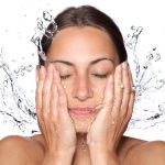 young female splashing water on her face