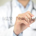 concept of a male doctor writing hair transplant on screen