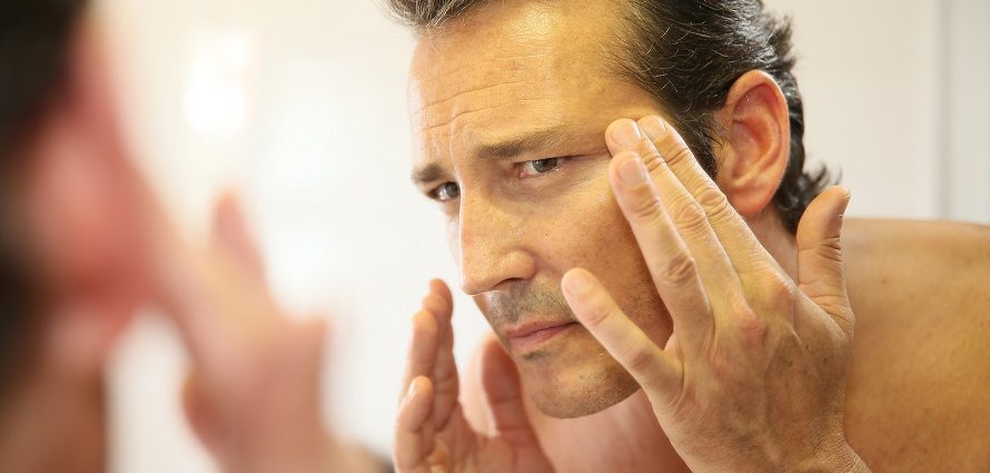 man looking at his wrinkles in mirror