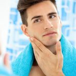 young male assessing his jaw in the mirror