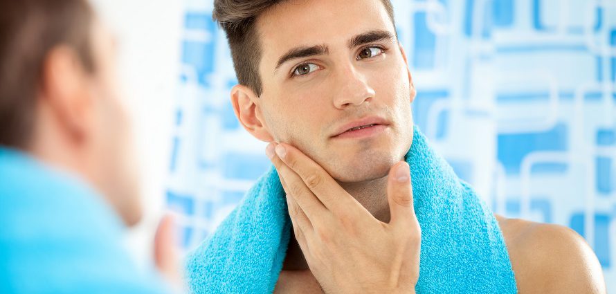 young male assessing his jaw in the mirror